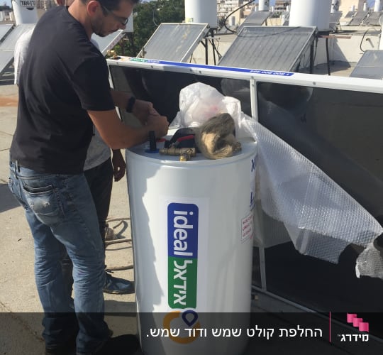 שני אנשים מתקינים דוד שמש על גג עם קולטים.